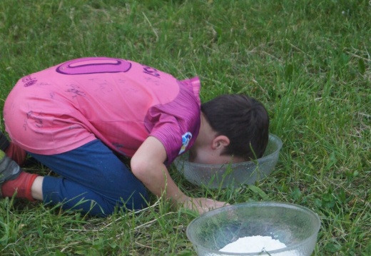 Kind fischt Schoggistängeli aus Wasserschale