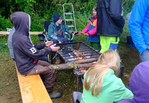 Leiter und Kinder sitzen am Morgen an der Feuerschale