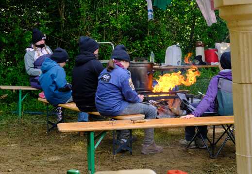 Kinder und Leiter sitzen am Feuer